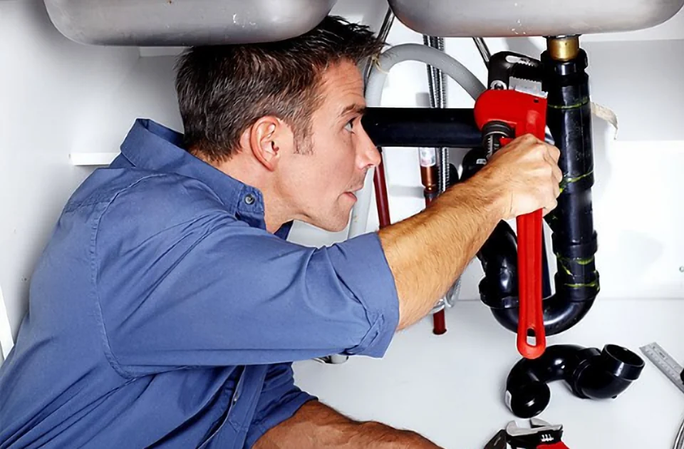 Plumber tightening a sink drain pipe with a pipe wrench, plumbing repair in Ajax