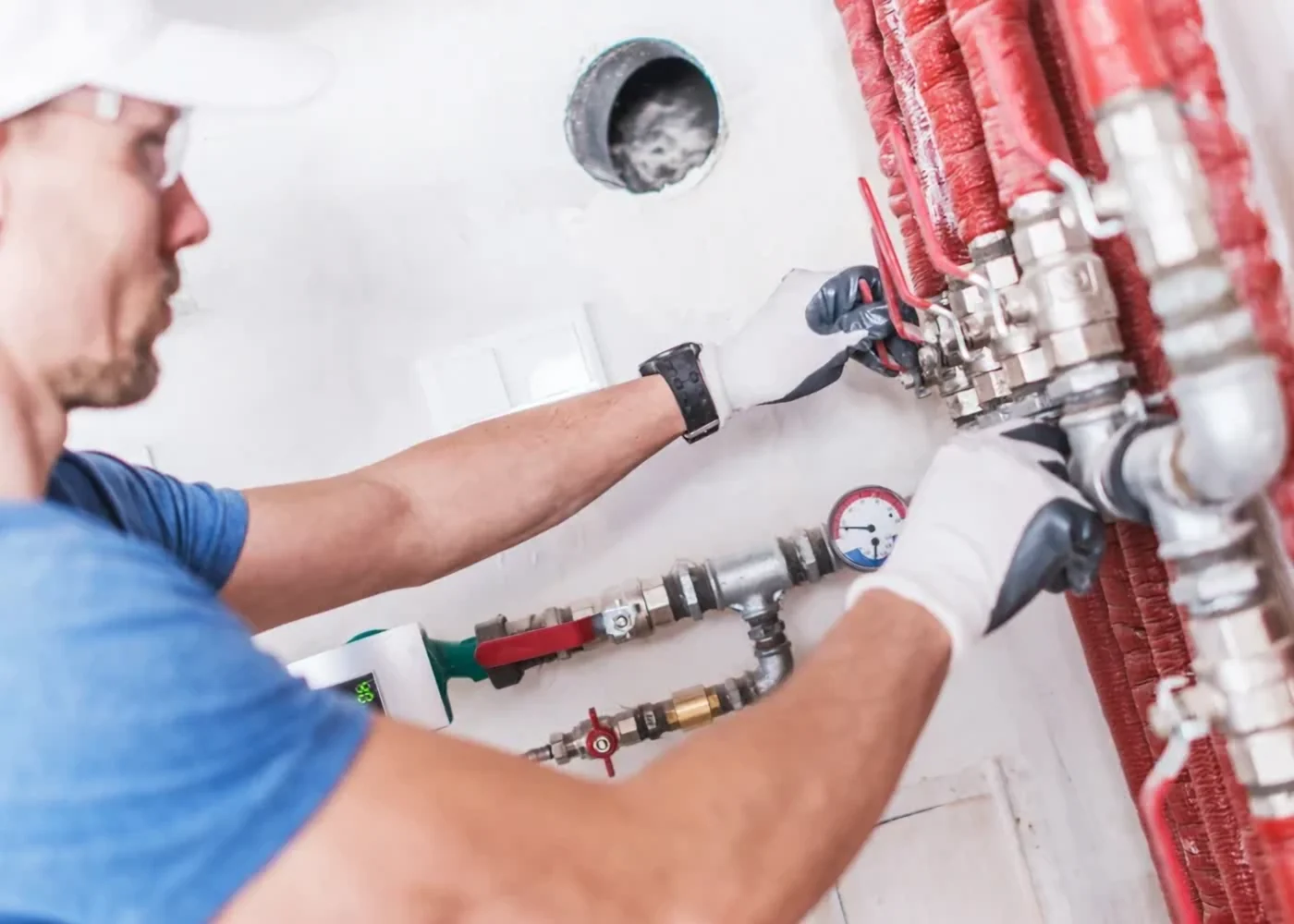 Plumber connecting a radiant floor heating manifold with a pressure gauge