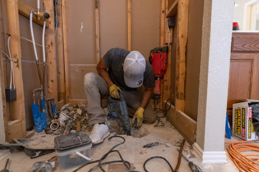 Plumber opening a bathroom floor to replace drain piping during a plumbing renovation in Toronto